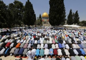 The Dome of Rock is seen in the background as Palestinian men pray  in Jerusalem's Old City