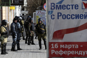 Members of a Crimean self-defence patrol near a referendum poster on a street in Simferopol
