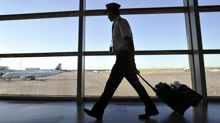 An Air Canada pilot walks to his plane at the International airport in Calgary, September 20, 2011. Flight attendants at Air Canada, Canada's largest airline, can legally walk off the job at midnight tonight. Flight attendants are threatening to strike over wages and better working conditions. REUTERS/Todd Korol (CANADA - Tags: BUSINESS EMPLOYMENT TRANSPORT CIVIL UNREST)