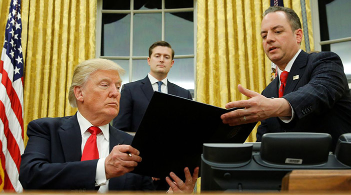 Trump hands Priebus an executive order that directs agencies to ease the burden of Obamacare, after signing it in the Oval Office in Washington