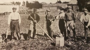 На одной – несколько мужчин с лопатами стоят в ряд на бугристом, поросшем травой пригорке.
