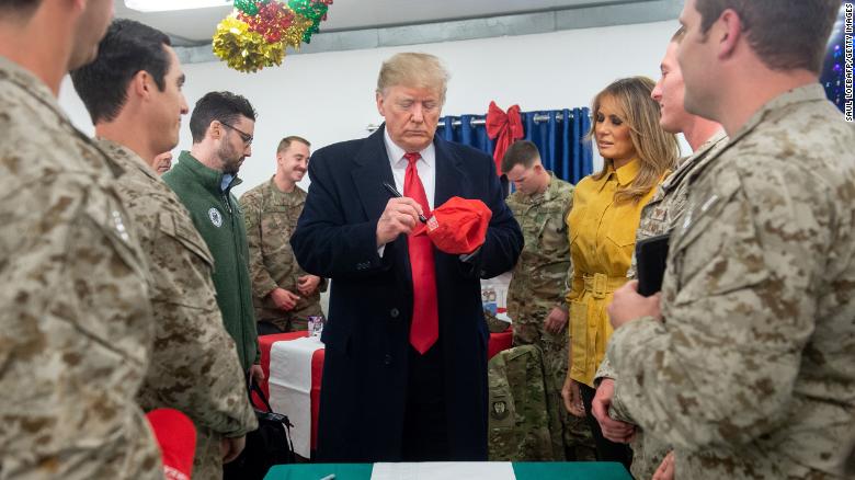 US President Donald Trump signs a hat as First Lady Melania Trump looks on as they greet members of the US military during an unannounced trip to Al Asad Air Base in Iraq on December 26, 2018. - President Donald Trump arrived in Iraq on his first visit to US troops deployed in a war zone since his election two years ago (Photo by SAUL LOEB / AFP)        (Photo credit should read SAUL LOEB/AFP/Getty Images)
