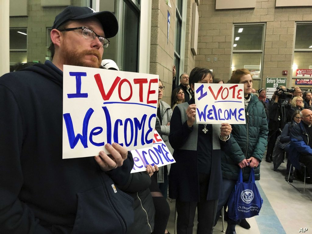 Residents in support of continued refugee resettlement hold signs at a meeting in Bismarck, N.D., Monday Dec. 9. 2019. Several church leaders are urging Burleigh County not to be the nation's first to refuse new refugees since President Donald Trump ordered that states and counties should have the power to do so. (AP Photo/James MacPherson)